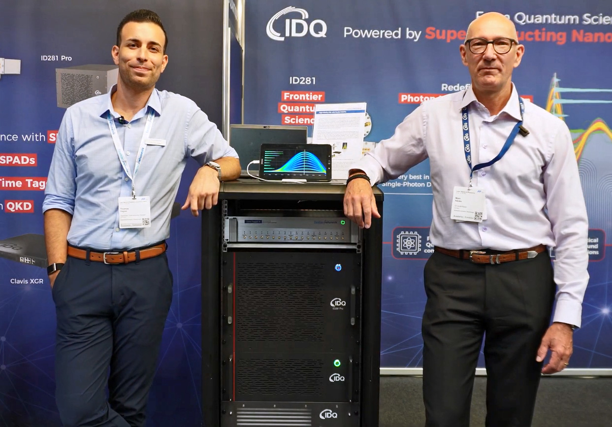 Thomas Hayes (Swabian Instruments President, Americas) and Marc Nikles (ID Quantique, CRO) at the ID Quantique exhibition booth for Laser World Photonics 2025. A rack standing in between the two of them displays Swabian Instruments Time Tagger X,  ID Quantique p-SNSPDs, and a  photon number resolving measurement, as part of the newest partnership.