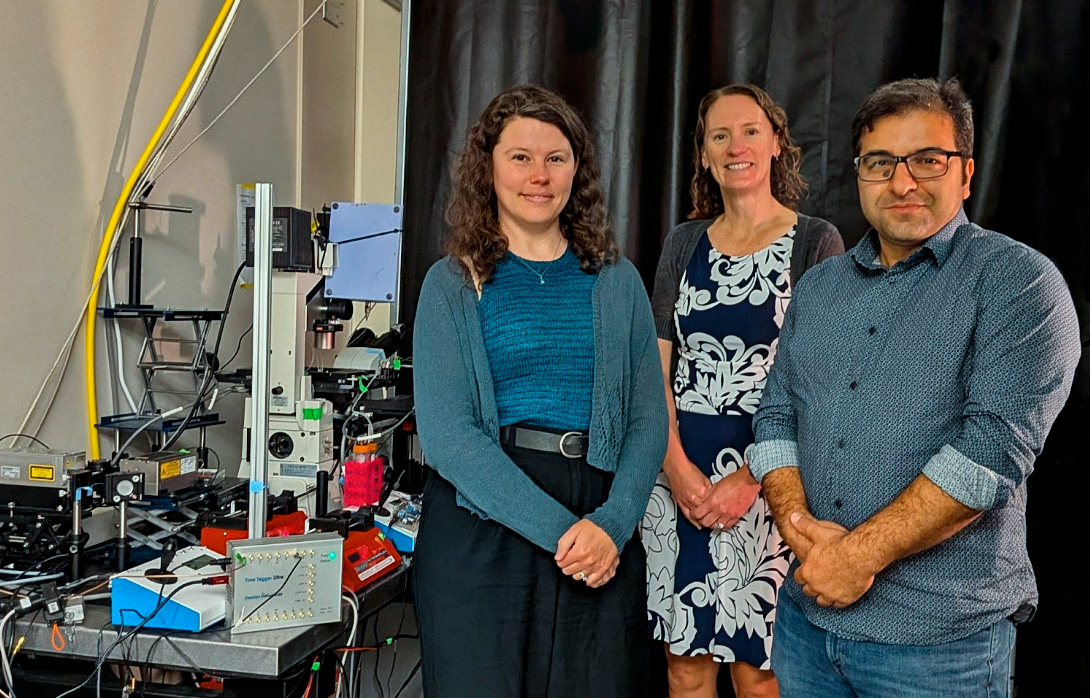 Three researchers of Melissa Skala’s group (left ot right: Amani Gillette, Melissa Skala, and Kayvan Samimi) posing in front of their experimental setup, with the Time Tagger Ultra to Amani’s right.